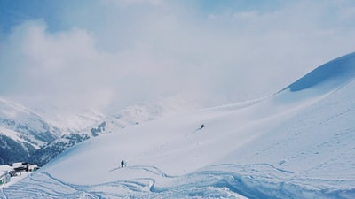 两个人白天在白雪覆盖的山上徒步旅行